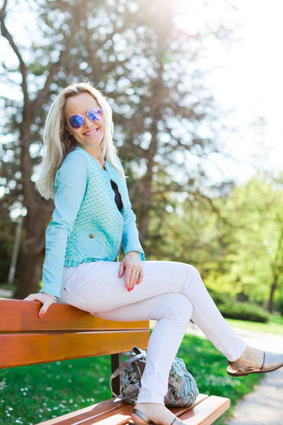 Blond attractive woman with sun glasses siting on bench - Φωτογραφία, εικόνα