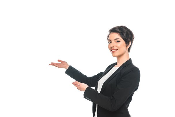 attractive mixed race businesswoman gesturing and smiling at camera isolated on white - 写真・画像