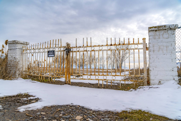 Yksityinen omaisuus, jolla on luvaton tunkeutuminen merkki ruosteisella portilla talvella katsottuna
 - Valokuva, kuva