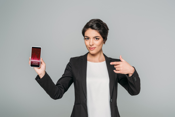bela mulher de negócios mista mostrando smartphone com cursos de negociação aplicativo na tela isolado em cinza
 - Foto, Imagem