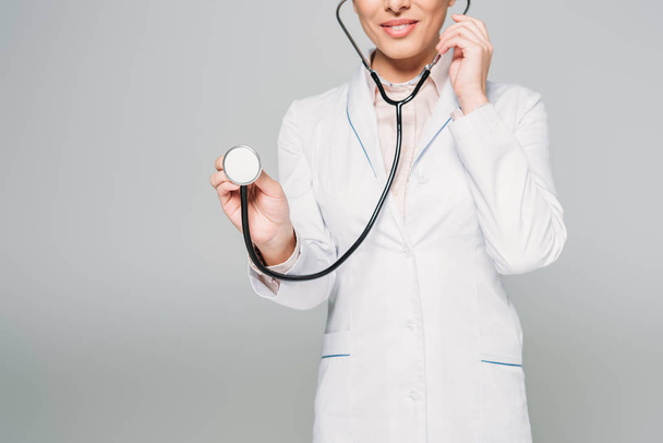 cropped shot of mixed race doctor using stethoscope isolated on grey - 写真・画像