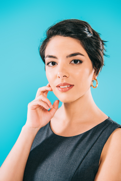 portrait of beautiful mixed race woman looking at camera while holding hand near face isolated on blue - Fotografie, Obrázek