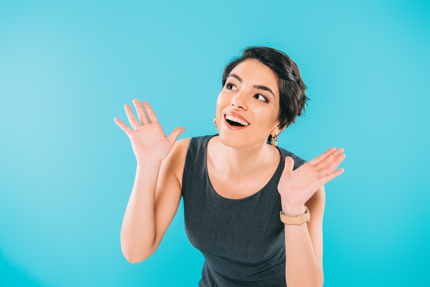excited mixed race woman gesturing while looking away isolated on blue - Photo, Image