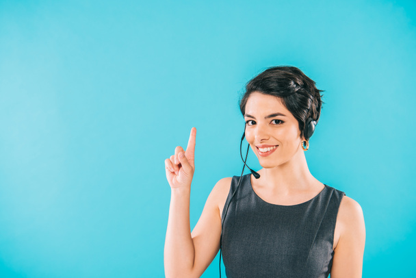 cheerful mixed race call center operator in headset showing idea sign isolated on blue - Photo, Image
