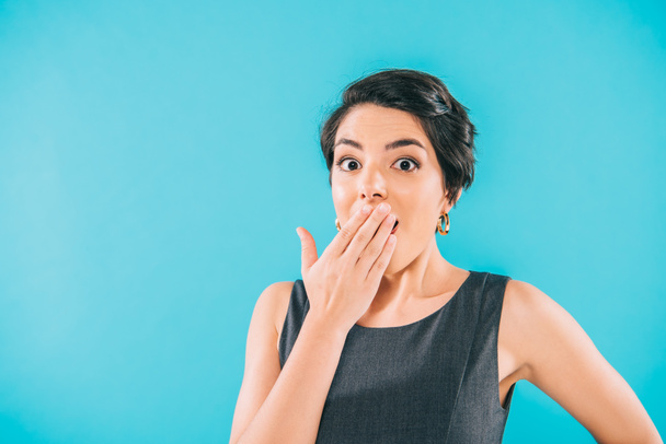 schockierte Mischlingshündin bedeckt Mund mit Hand, während sie isoliert auf blauem Grund in die Kamera schaut - Foto, Bild