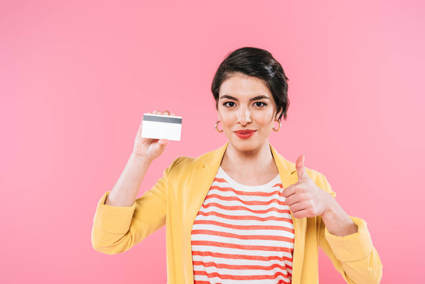 beautiful mixed race woman holding credit card and showing thumb up isolated on pink - Fotografie, Obrázek