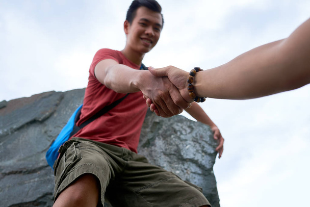 Túró, amely kezét a barátjának, hogy segítsen neki a hegymászó a falon - Fotó, kép