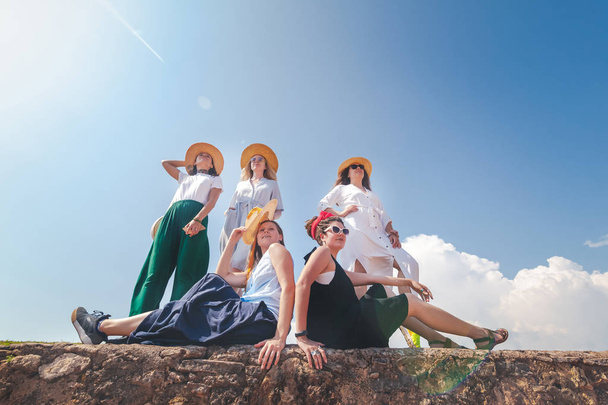 Group of happy joyful young stylish girls travel together, in hats against a blue sky - Fotó, kép