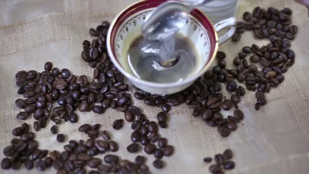 het toevoegen van suiker in een kopje verse espresso koffie-koffie korrels achtergrond - Video