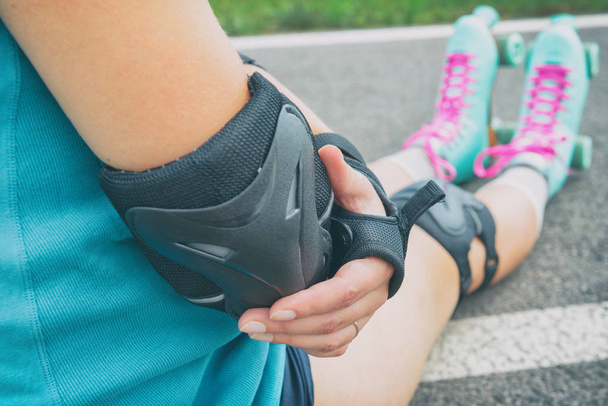 Woman rollerskater putting on elbow protector pads on her hand - Photo, Image