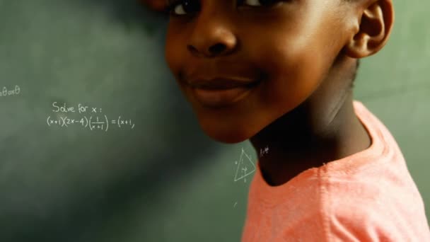 Digital composite of an African-American boy holding a chalk at the board while mathematical equations move in the screen - Video