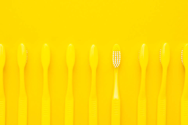 minimalist photo of yellow toothbrushes turned down and one of them turned up - Foto, imagen