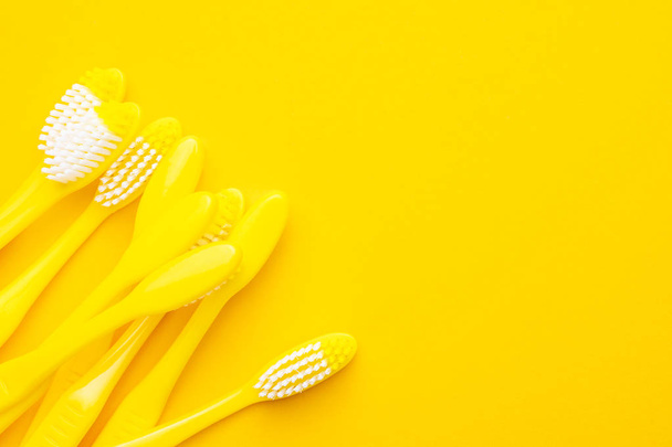 plastic toothbrushes on yellow background - Foto, imagen