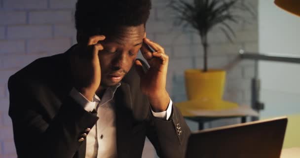 Tired and stressed businessman with headache working late at his office. He working hard on his laptop at night. Office worker, freelancer. Workaholic. - Кадры, видео