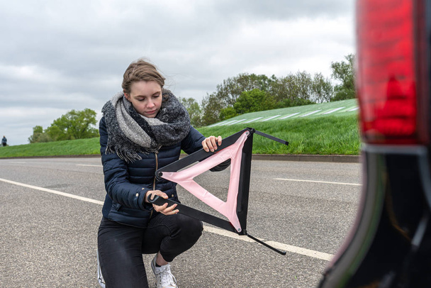 Женщина с поломкой машины установила предупреждающий треугольник
 - Фото, изображение