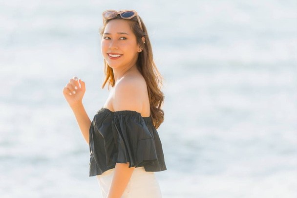 Muotokuva kaunis nuori aasialainen nainen onnellinen ja hymyillä rannalla meri ja valtameri matka ja loma käsite
 - Valokuva, kuva