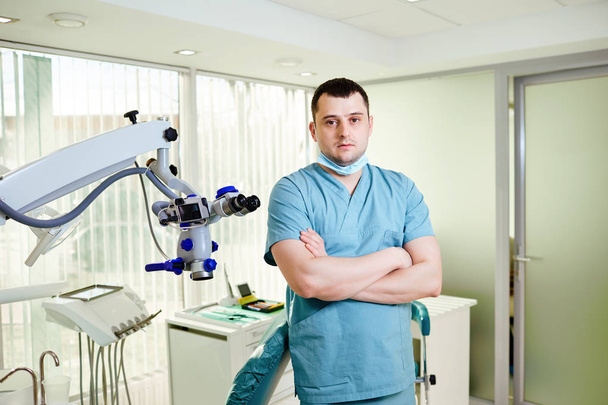 A male dentist is standing with a microscope - Zdjęcie, obraz