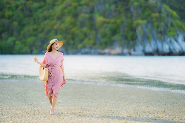 Portrait young beautiful asian woman walk smile and happy on the beach sea and ocean for leisure travel in holiday vacation - Photo, Image