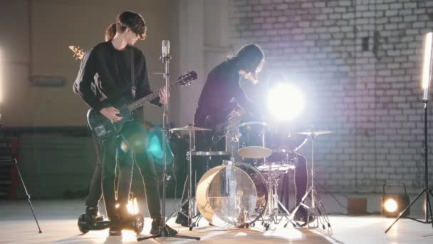 Uma repetição. Um grupo jovem de pessoas tocando música rock em um hargar brilhante
 - Filmagem, Vídeo