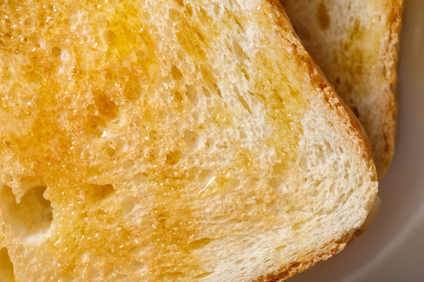 close up view of toasts with honey on white plate - Foto, afbeelding