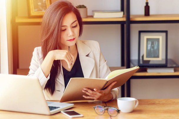 young Asian business woman working at workplace. beautiful Asian woman in casual suit working with reading book, prepare for meeting or interview in modern office. freelance, start up business in Asia - Foto, Bild