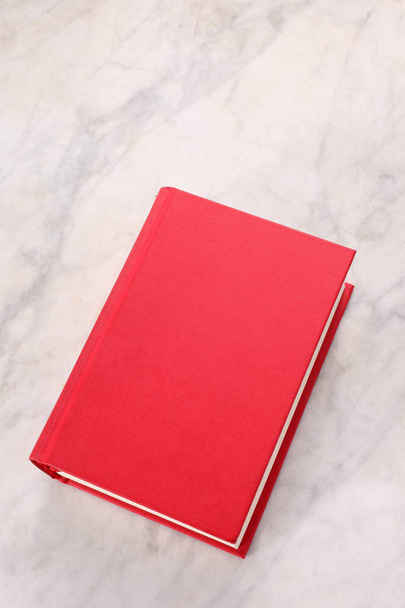 κόκκινο βιβλίο να ξεκουραστεί σε μαρμάρινη φόντο με χώρο αντιγραφής για το κείμενό σας - Φωτογραφία, εικόνα