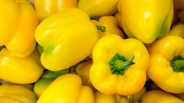 Macro image of lots of fresh yellow papricas or bell peppers. Texture or pattern of fresh ripe vegetables - Photo, Image