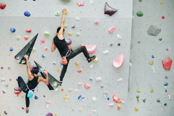 Pari harjoitellaan kalliokiipeilyä keinotekoisella seinällä sisätiloissa
 - Valokuva, kuva