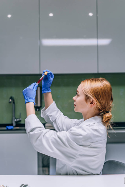Investigadora médica ou científica feminina a olhar para um tubo de ensaio num laboratório
. - Foto, Imagem