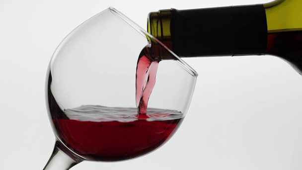 Rose wine. Red wine pour in wine glass over white background. Slow motion - Imágenes, Vídeo