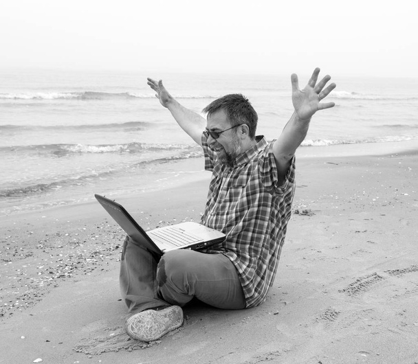 Empresário emocional com laptop na praia
 - Foto, Imagem