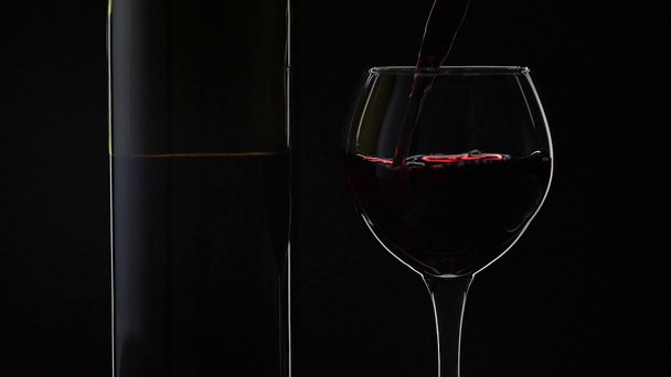 Růžové víno. Červené víno nalije do skleněného vína přes černé pozadí. Zpomaleně - Záběry, video