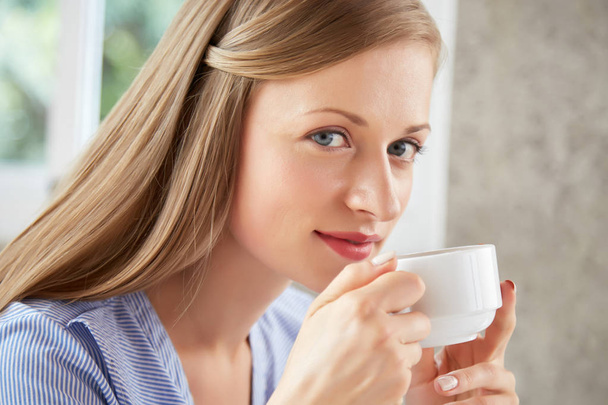 Прекрасна молода жінка насолоджується чашкою смачного гарячого чаю
 - Фото, зображення