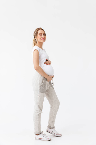 Beautiful young pregnant woman posing isolated over white wall background. - Фото, зображення