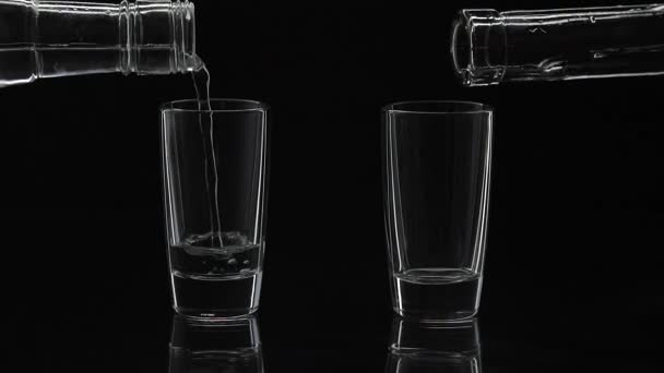 zwei Schuss Wodka aus einer Flasche in Glas gießen. schwarzer Hintergrund - Filmmaterial, Video