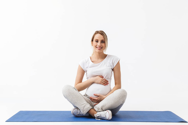 Hamile yoga fitness kadın beyaz duvar arka plan üzerinde izole poz egzersizleri yapmak. - Fotoğraf, Görsel