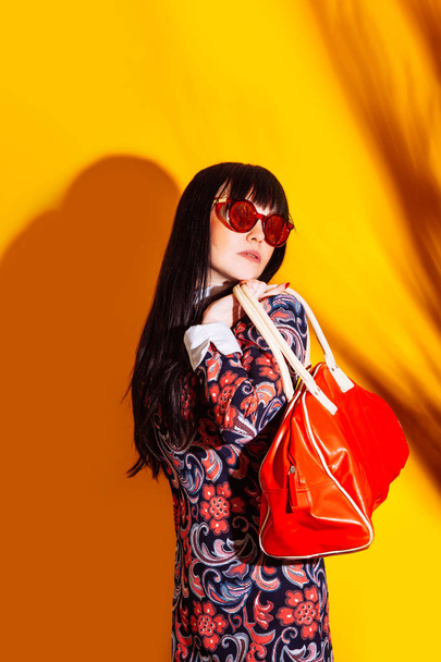 shopper woman yellow background red shadow bag brunette glasses funny shopping - Foto, Imagem