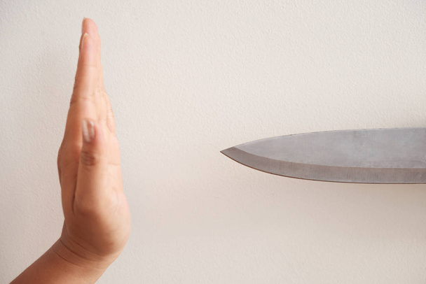 Crop ręce anonimowej kobiety pokazując gest zatrzymania przed ostrym nożem - Zdjęcie, obraz