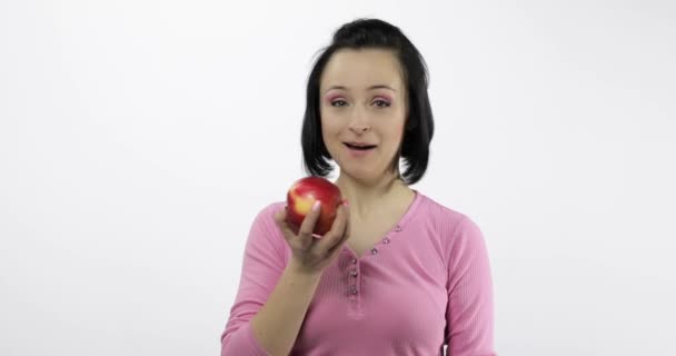 Young woman eating apple and says yum. Girl takes first bite and say wanna bite - Materiał filmowy, wideo