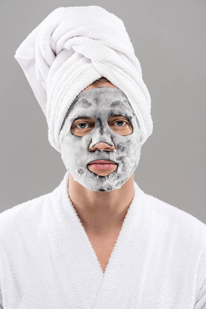 front view of man in bathrobe with facial mask isolated on grey - Foto, imagen
