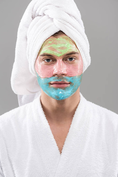 Vooraanzicht van de mens in badjas met gezichtsmasker geïsoleerd op grijs - Foto, afbeelding