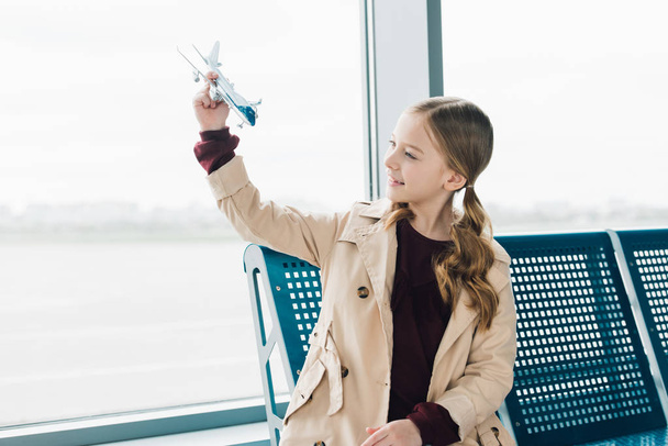 souriant préadolescent tenant jouet avion dans l'aéroport salon de départ
 - Photo, image