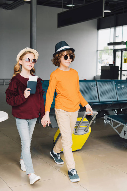 preteen children in sunglasses with baggage and passport in waiting hall - Photo, Image