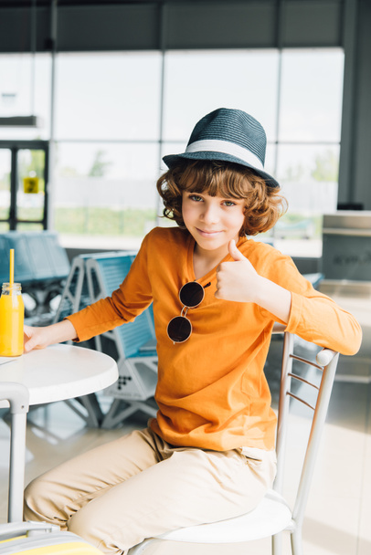 preteen boy showing thumb up in airport and looking at camera - Foto, imagen
