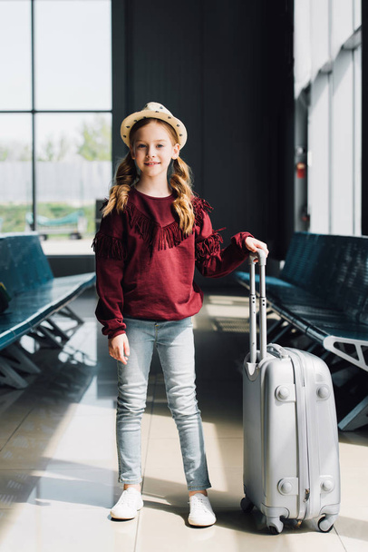 smiling preteen kid with suitcase in waiting hall in airport - Foto, Imagem