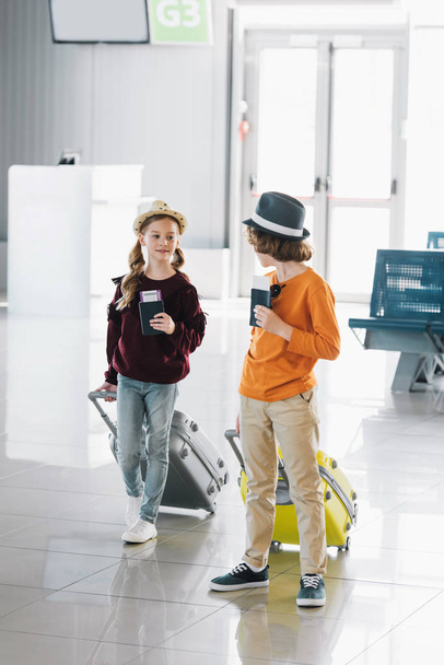 preteen children with suitcases, air tickets and passports in waiting hall - Photo, Image
