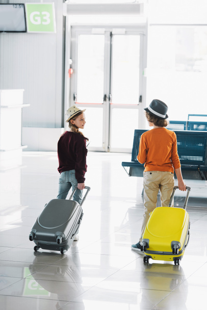 Cropped view of preteen kids with suitcases in waiting hall in airport - Photo, Image
