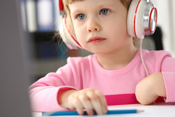 Küçük kız giyen kulaklık Mobil bilgisayar kullanımı - Fotoğraf, Görsel