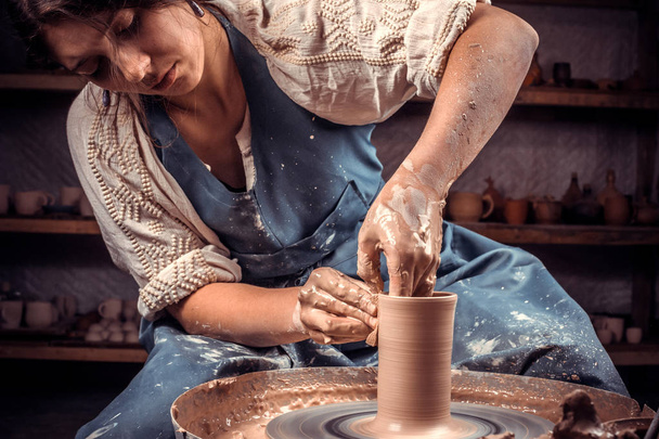 Charmante Keramikerin zeigt, wie man mit Ton und Töpferscheibe arbeitet. Herstellung von Keramikgeschirr. - Foto, Bild