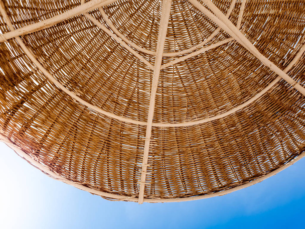 Крупный план части соломенного зонта, защищающего от солнца на пляже от синего неба. Удобный имидж для летнего отдыха или отпуска. Место для смс. Копирование пространства
. - Фото, изображение